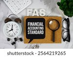 FAS - Financial Accounting Standard acronym with calculator, alarm clock and magnifying glass, Business and Financial concept background