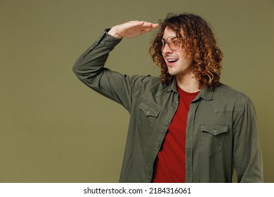 Fascinating Exultant Smiling Long Curly Hair Young Brunet Man 20s Wears Khaki Shirt Put Hand Palm To Forehead Looking Aside As Notices Someone Isolated On Plain Olive Green Background Studio Portrait