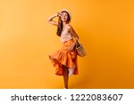 Fascinating red-haired lady expressing positive emotions. Happy ginger girl in orange skirt dancing with smile.