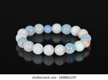 Fashion accessories. Jewelry on black glassy surface. Gemstone bracelets. Natural stones beads.