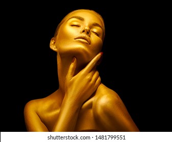 Fashion art Golden skin Woman face portrait closeup. Model girl with holiday golden Glamour shiny professional makeup. Gold jewellery, jewelry, accessories. Beauty gold metallic body, Lips and Skin