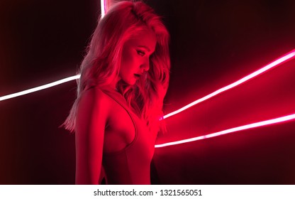 fashion art photo of sexy girl dressed in red in the night-club. Perfect female body with neon lettering on the background. Night club girl concept