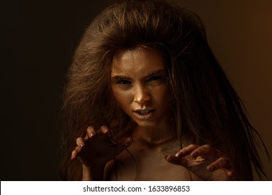 Fashion art portrait of female actress plays the role of a cat, lion or tiger. concept of wild animal inside every woman. beaty woman with gold metallic body and hair on dark background.