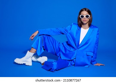 Fashion asian female model in blue suit, white boots and sunglasses. Asian fashion