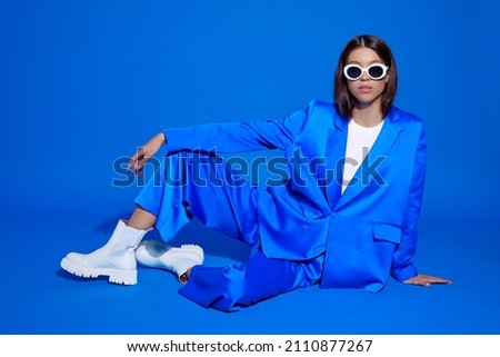 Fashion asian female model in blue suit, white boots and sunglasses. Asian fashion