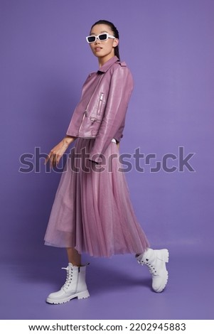 Fashion asian female model. Lilac leather jacket, lilac skirt, white boots, sunglasses. Asian fashion
