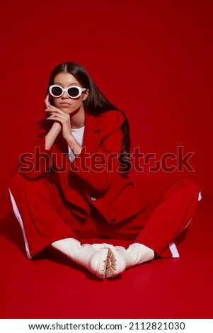 Fashion asian female model in red suit, white boots and sunglasses. Asian fashion