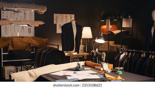 Fashion atelier with clothes sketches and tools, sewing machines and instruments used to create tailored items at workstation. Empty tailoring space with drawings and materials. Handheld shot. - Powered by Shutterstock