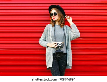 Fashion autumn portrait woman holds retro camera on a red background - Shutterstock ID 709746994