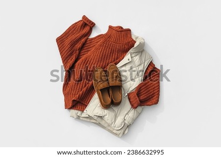 Fashion autumnal outfit. Knitted brown sweater with down vest jackets and loafers. Women's warm jumper, stylish autumn or winter clothes. Cozy fall look. Flat lay, top view, overhead. 