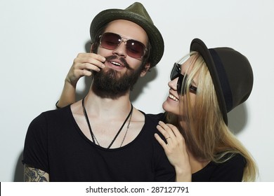 Fashion Beautiful Happy Couple In Hat Wearing Trendy Glasses Together. Hipster Boy And Girl. Bearded Young Man And Blonde In Sunglasses