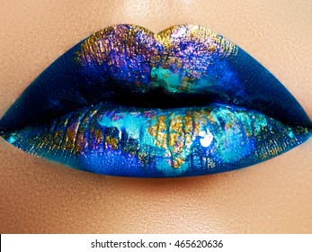 Fashion and beauty. Creative lip makeup. Artistic make-up. Beautiful macro shot of female plump lips. Closeup. Shiny glossy lips with a different texture and colors. Liquid gold and glitter