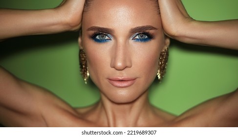 Fashion Beauty Portrait Of A Mature Woman With Smokey Eyes Make Up Wearing Golded Jewerlys Posing Against Green Background.