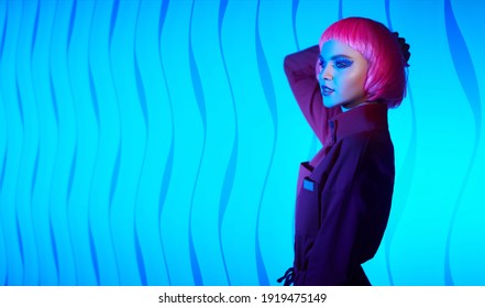 Fashion beauty trends. Portrait of a gorgeous young woman with bright glitter makeup and pink hair posing in mixed color neon light. Makeup cosmetics and hairstyle. Copy space. 