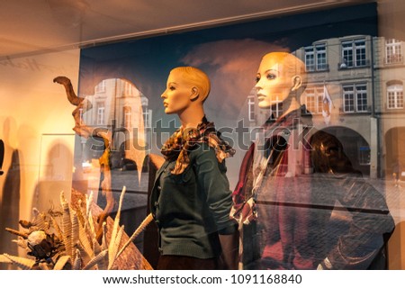 Fashion behind glass, windowshopping in the evening gives beautiful reflections