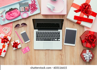 Fashion blogger desktop with laptop, credit card, touch screen mobile devices, gift boxes and beauty accessories, flat lay