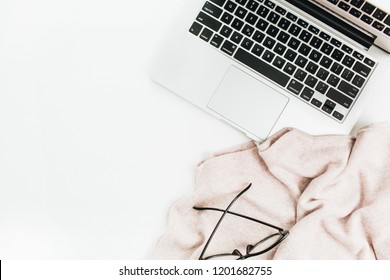 Fashion blogger home office workspace with laptop, glasses and sweater on white background. Flat lay, top view minimal work concept.