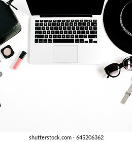 Fashion blogger office desk with laptop and black styled woman clothes and accessories collection on white background. Flat lay, top view.
