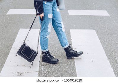 fashion blogger outfit details. fashionable woman wearing ripped vintage denim jeans, suede jacket, black biker boots -ankle shoes and black trendy handbag. detail of a perfect fall fashion outfit. 
