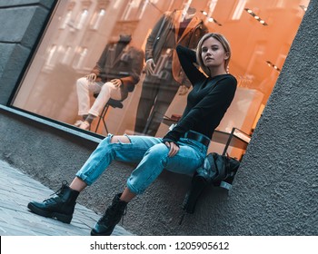 Fashion Blonde Model Wearing Ripped Boyfriend Jeans, Black Golf, Boots Posing In The City Street. Fashion Urban Outfit. Casual Everyday Clothing Style.