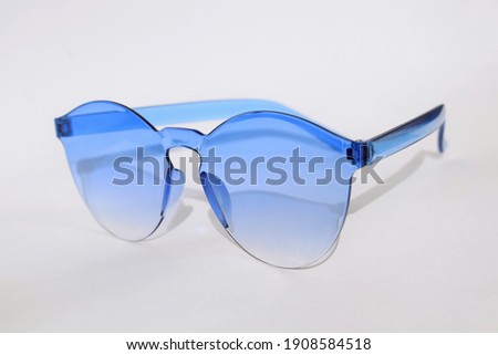 Fashion blue sun glasses (sunglasses) isolated on white. Blue spectacles or glasses on modern background. Glasses with transparent blue round sun lenses isolated object. Hipster woman fun sunglasses