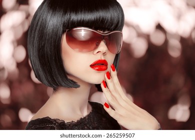 Fashion brunette woman in sunglasses. Black bob hairstyle. Red lips makeup. Glamour girl posing over holiday background.