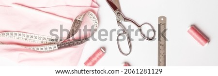 Fashion business. Dressmaker's workplace. Clothing designer's work desk with sewing tools,pink fabric, scissors. Tailoring. Banner