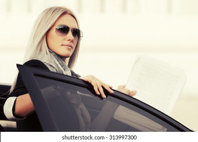 Fashion business woman with financial papers by her car 