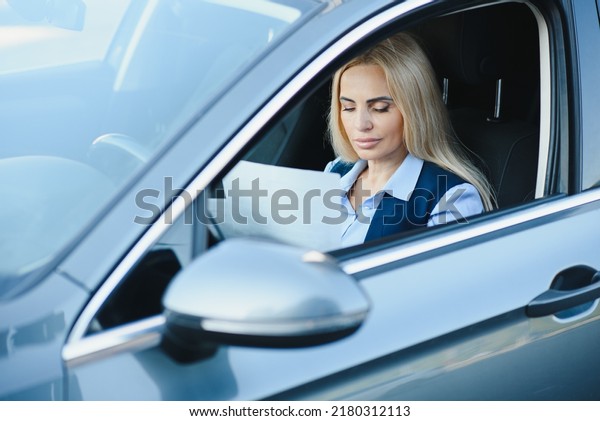 Fashion\
business woman with financial papers by her\
car.