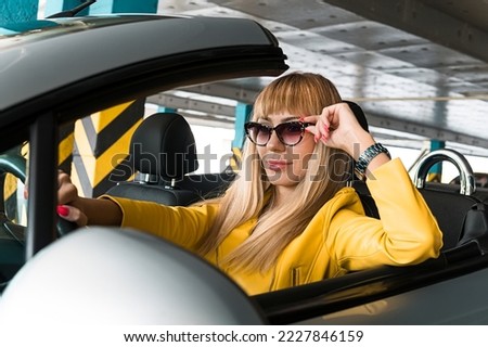 Fashion business woman with her car. Blonde woman Parking. Rich successful business woman in a cabriolet