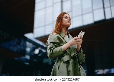 Fashion business woman with phone in hand in trendy clothes walking around town near office buildings, work online shopping technology - Powered by Shutterstock