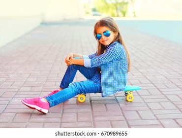 Fashion Child Little Girl Sitting On The Skateboard In The City