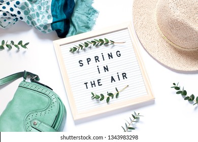 Fashion clothes concept frame with a felt board with text "Spring in the air" on the white background. top view. Copy space