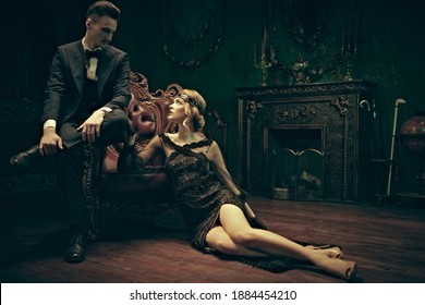 Fashion Clothes, Make-up And Hair In Luxurious Retro Style. Handsome Man And Beautiful Young Woman In The Style Of The 1920s In Rich Vintage Apartments. 