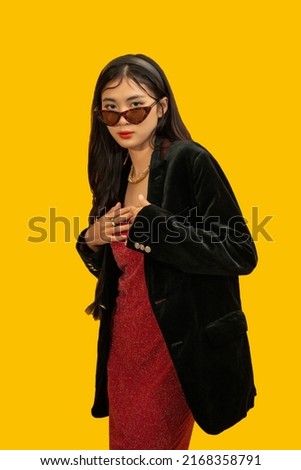 Fashion concept, Fashionable woman wear sunglasses and red dress to posing with oversize black coat.