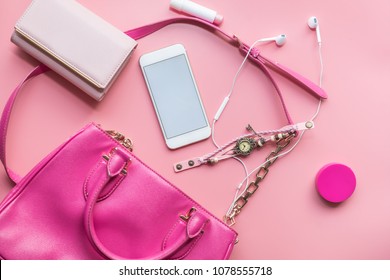 Fashion Concept : Flat Lay Of Pink Woman Bag Open Out With Cosmetics, Accessories And Smartphone On Pink Background