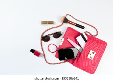 Fashion Concept : Flat Lay Of Purple Leather Woman Bag Open Out With Sunglasses And Smartphone On White Background.