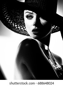 fashion concept - portrait of a beautiful woman in big hat and sunglasses in mixed contrast light