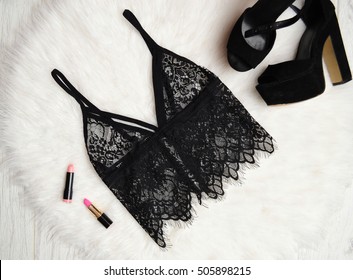 Fashion concept. Women's accessories: lace bra, shoes and lipstick. White background, top view.