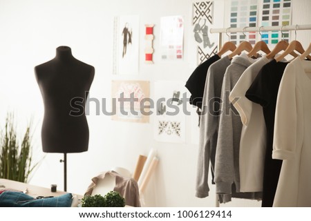 Fashion creative design studio cozy interior concept with mannequin dummy and exclusive unique stylish fashionable trendy clothes on hangers, dressmaking workplace, tailor shop, sewing workshop