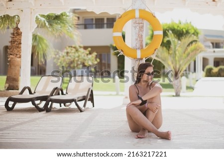 Fashion cute young teenage girl or woman posing in summer swimsuit with a lifebuoy. Trendy girl posing. Funny and positive woman in sunglasses