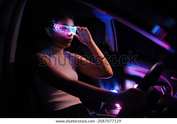 Fashion cyberpunk girl\
drive a supercar. Asian woman  with future digital glasses,future\
technology concept