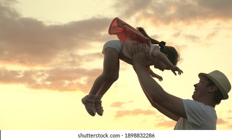 Fashion Dad In Hat And Small Healthy Child Play Together, Laugh And Hug. Dad Throws Up A Happy Daughter In The Blue Sky. Happy Family Travels. Baby In Arms Of Parent. Dad Day Off. Happy Family