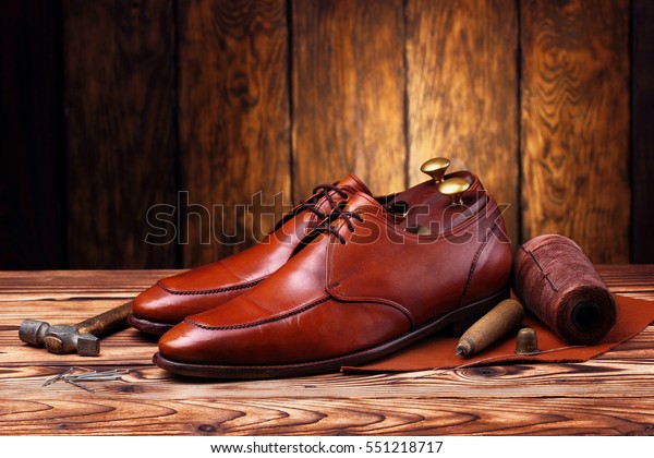 Fashion derby shoes handmade and shoes maker\
tools (hammer, awl, nails, skien of thread).Wooden\
background.Concept\
cobbler