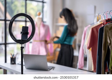 Fashion designer is adjusting clothes on a mannequin in preparation for a live stream - Powered by Shutterstock