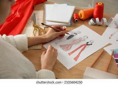 Fashion Designer Creating New Clothes In Sketchbook At Wooden Table, Closeup