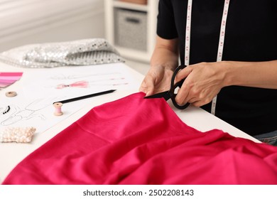 Fashion designer cutting pink fabric at table in workshop, closeup - Powered by Shutterstock