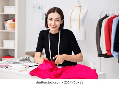 Fashion designer cutting pink fabric at table in workshop - Powered by Shutterstock