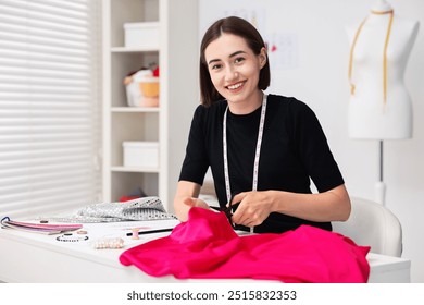 Fashion designer cutting pink fabric at table in workshop - Powered by Shutterstock