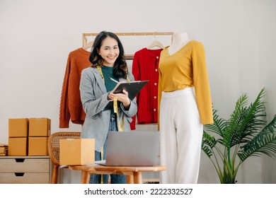 Fashion designer l young asian woman working using laptop, tablet and smiling while standing in workshop Responding on business  - Powered by Shutterstock